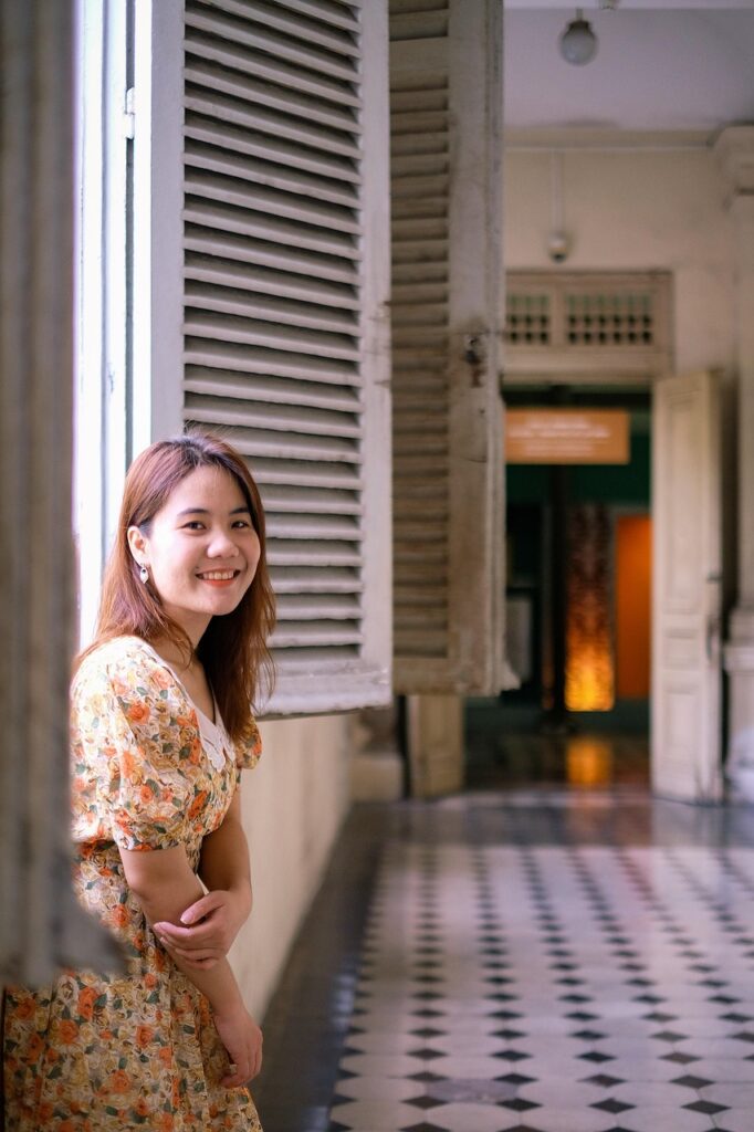 柔らかい光が差し込む美術館の回廊でほほえむ女性。明るい花柄ワンピースが春の美術館コーデにぴったり。